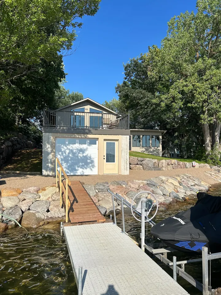 Boulder shoreline beside a lake shed with a dock and boat lift in the water